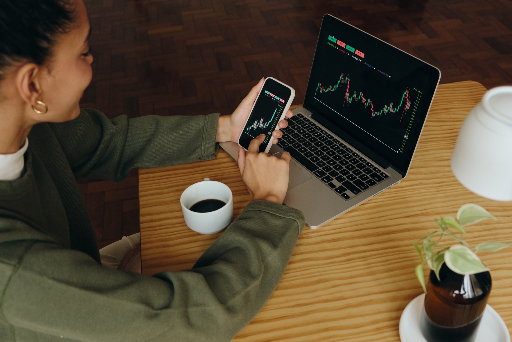 Woman Managing Stocks on Smartphone and Laptop